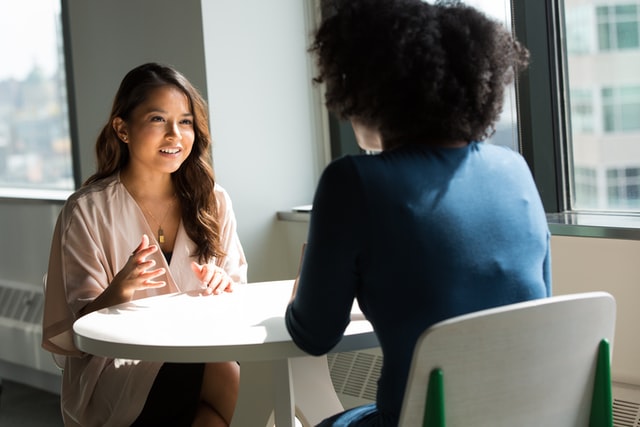 two women of colour in conversation at a private table